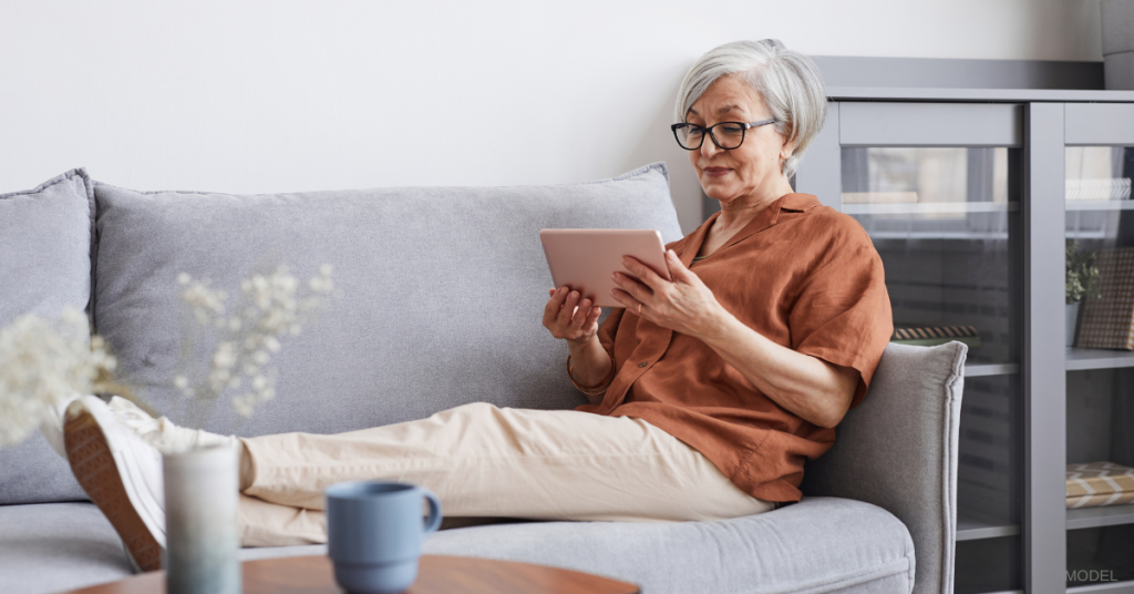 Mature woman relaxing on the couch reading (model)